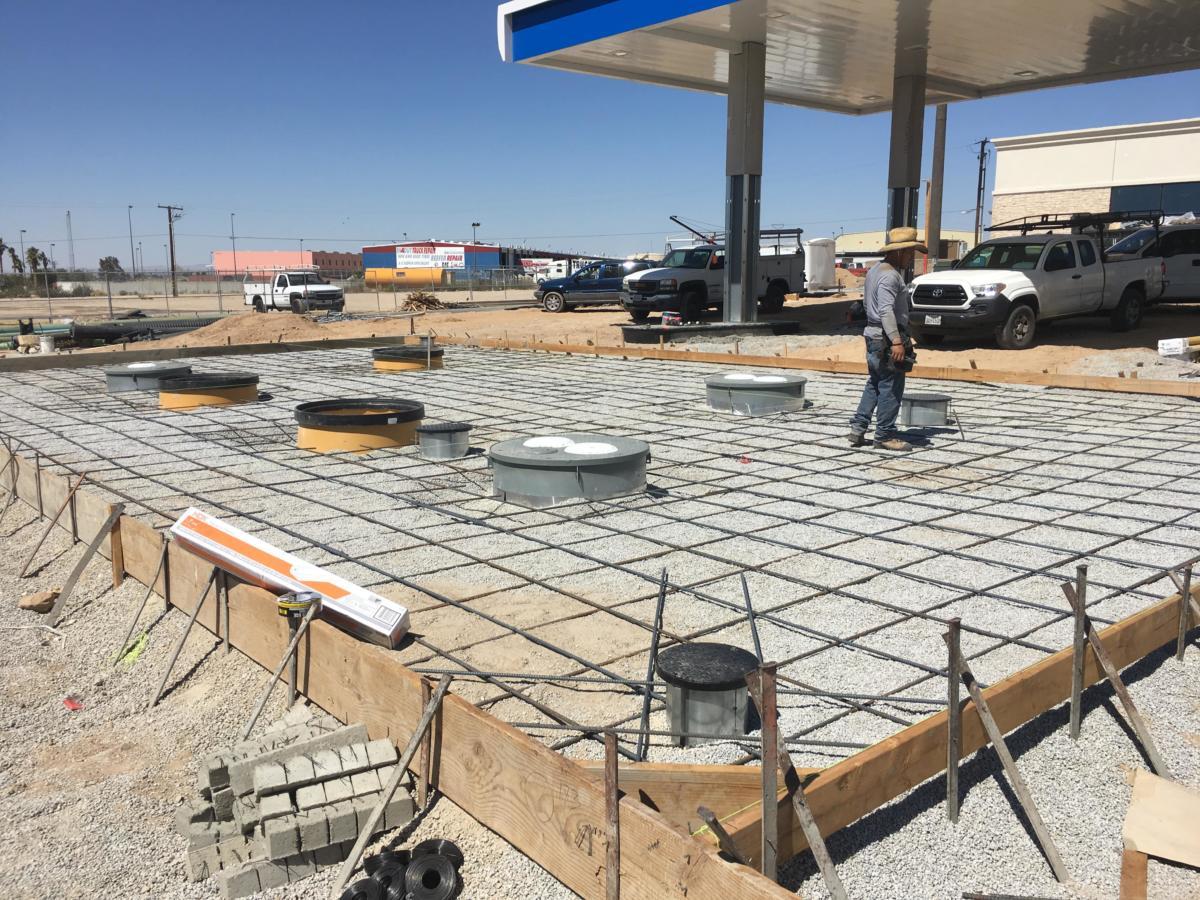 Rebar grid and underground tank fill ports at a gas station fuel island under construction